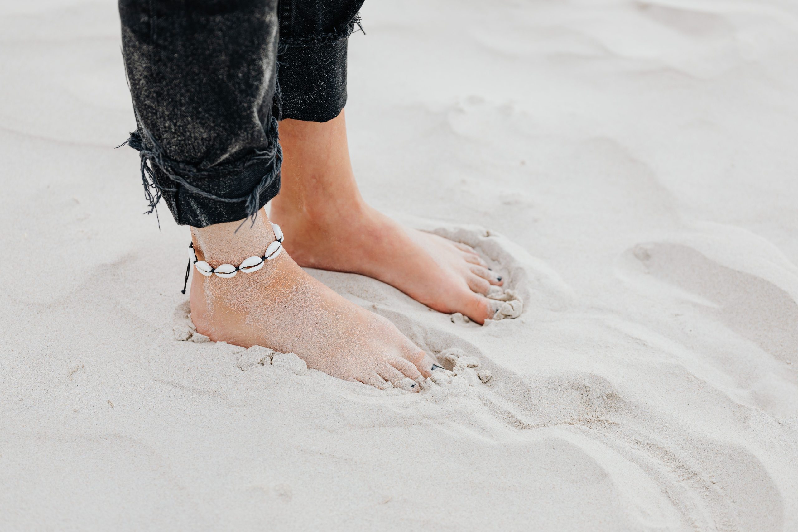 Pieds sur plage de sable portant chaîne de cheville