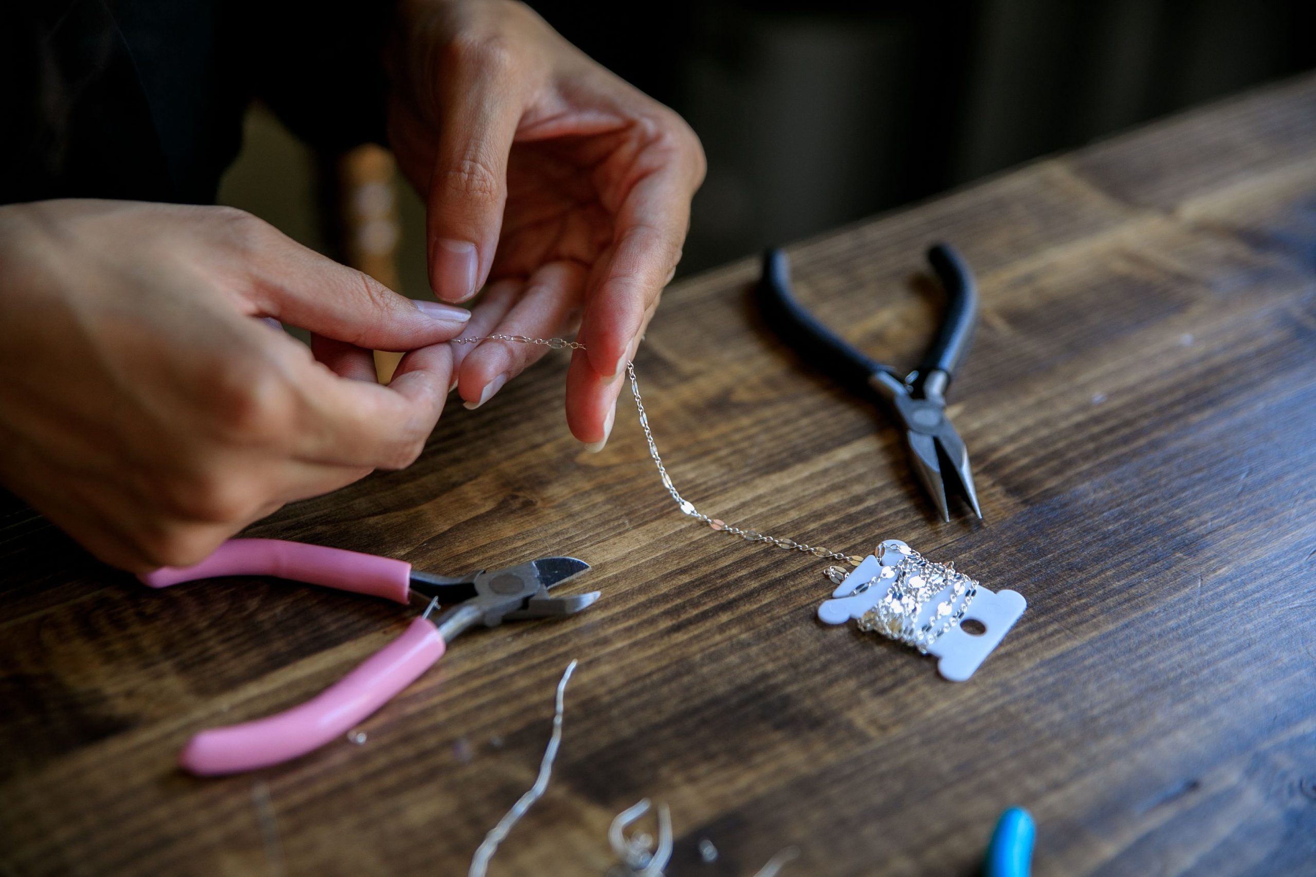 Mains façonnant un bijou avec pinces et fil