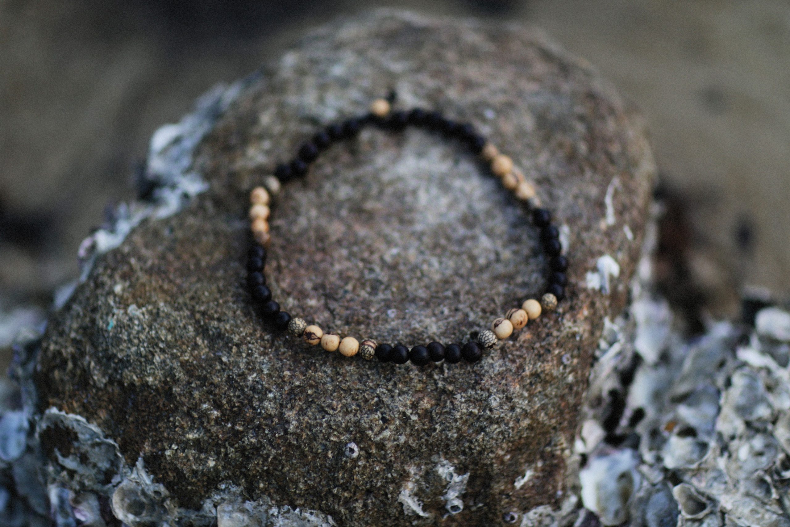 Bracelet de perles détaillé sur roche texturée en extérieur
