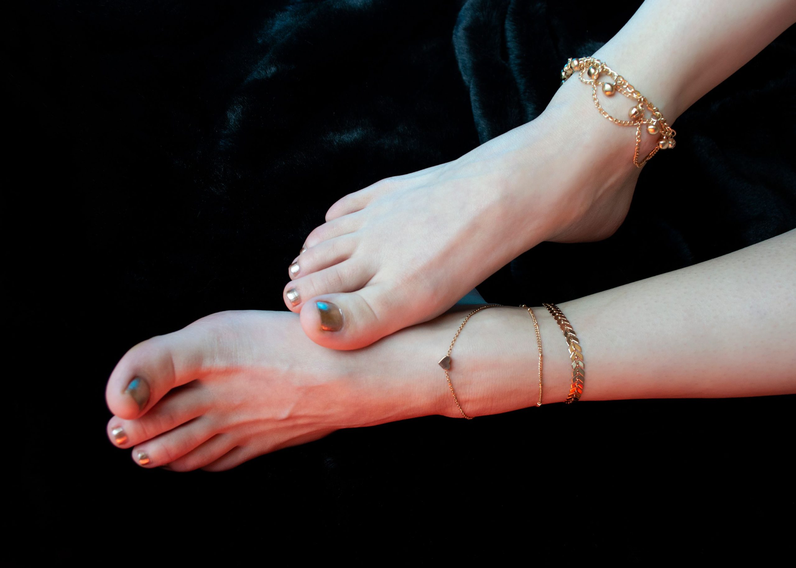 Jambes avec chaînes de cheville dorées sur fond noir