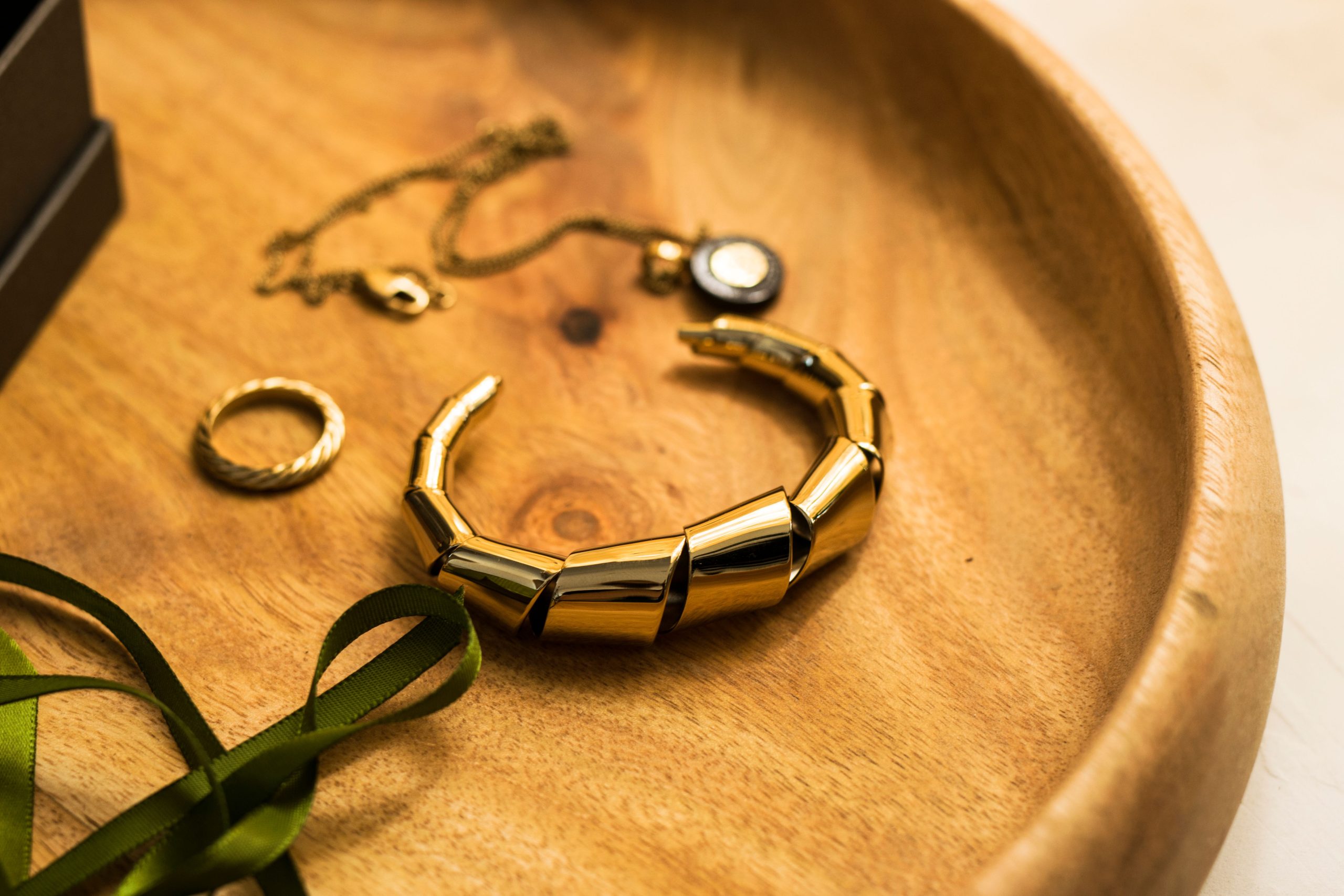 Bijoux dorés élégants : bracelet, bague et pendentif sur plateau bois